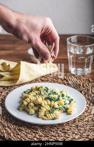 Pasta di fusilli con spinaci e ricotta guarnita con parmigiano grattugiato Formaggio su piatto bianco Foto Stock