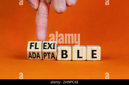 Simbolo adattabile o flessibile. L'uomo d'affari trasforma i cubi di legno e cambia la parola adattabile a flessibile. Bella tavola arancione sfondo arancione, poliziotto Foto Stock