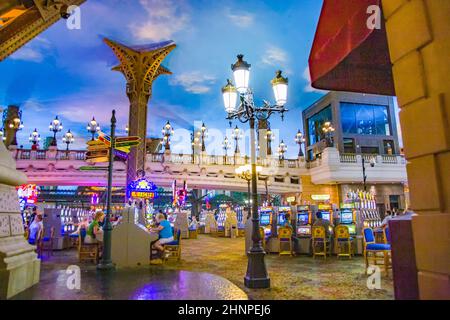 Giocatori seduti all'interno del casinò giocando con slot machine Foto Stock