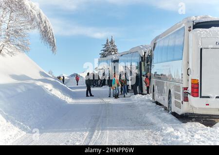 Gruppo sciistico con autobus nelle Alpi innevate Foto Stock