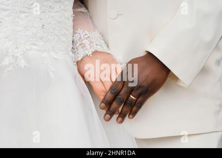 Coppia africana e causiana che tiene la mano con anello Foto Stock