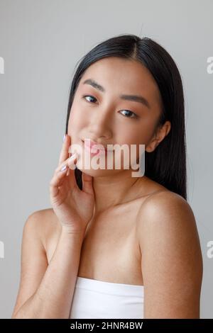 Giovane donna asiatica che tocca il viso con pelle perfetta Foto Stock