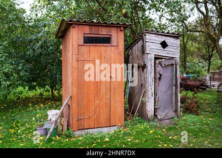 Vecchio e vicino ad esso un bagno rinnovato in legno nel giardino esterno all'aria aperta Foto Stock