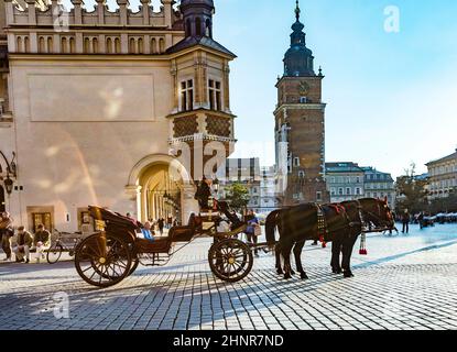 Carrozze a cavallo di fronte alla chiesa di Mariacki sulla piazza principale di Cracovia Foto Stock