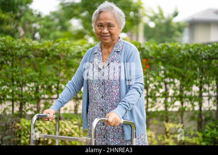 Anziano asiatico o anziana donna anziana uso walker con salute forte mentre camminando al parco in vacanza felice Foto Stock