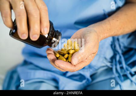 Medico asiatico che tiene e versa e tiene pillole di vitamina C medicina dal flacone al paziente per il trattamento di infezione in ospedale; farmacia farmacia con Foto Stock