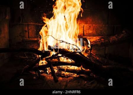 Fiamme che sorgono dal falò su pezzi di legno in natura di notte Foto Stock