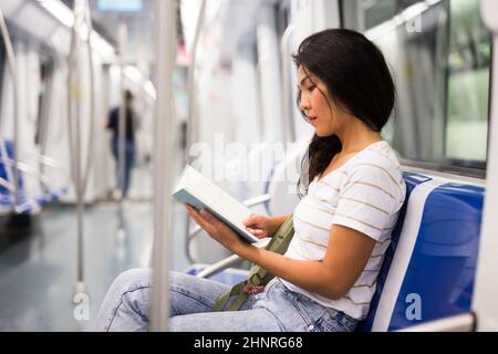 Donna che legge libro in metropolitana treno Foto Stock