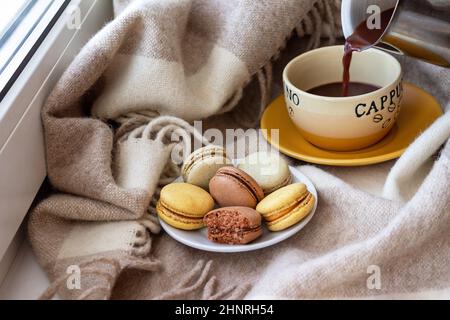 Mandorle da dessert francesi, il caffè viene versato in una tazza da un caffè Foto Stock