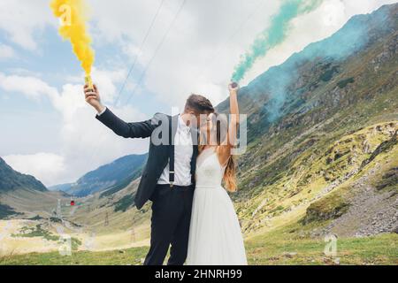 Sposarsi e sposarsi con le bombe fumogene di colore blu e giallo nel parco  estivo. La sposa e lo sposo con il fumo colorato sullo sfondo di Summe Foto  stock - Alamy