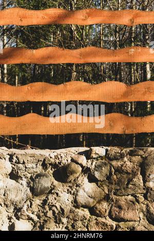 Legno e pietra di fondo. Scherma di legno e muro di pietra naturale nel parco Foto Stock