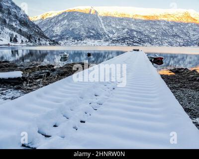 Molo innevato in un paesaggio invernale presso il lago dei fiordi di Framfjorden, Vestland, Vik, Norvegia. Foto Stock