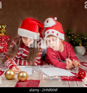 Felice ragazzo e ragazza scrivere una lettera a Babbo Natale. Foto Stock