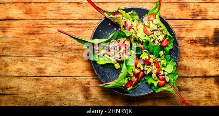 Insalata di avocado, pomodoro con salsa all'aglio in foglie di bietole. Insalata di vitamina estiva in piatto Foto Stock