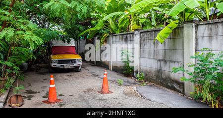 Abbandonata vecchia auto nella foresta tropicale a Bangkok Thailandia. Foto Stock