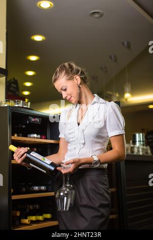 Simpatico sommelier femminile, cameriere di vino che sceglie il vino giusto per andare bene con il cibo in un ristorante Foto Stock