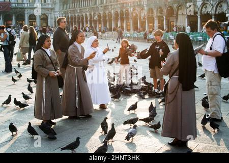 I noni in piazza San Marco nutrono un grande gregge di piccioni Foto Stock