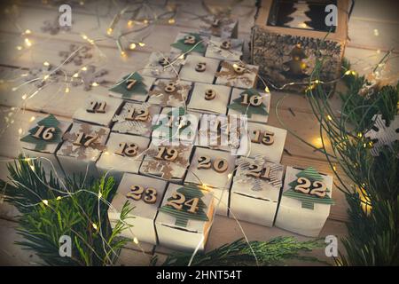 Calendario dell'avvento di natale in stile vintage. Cubetti sdraiati sotto forma di albero di natale con luci fairy. Primo piano con profondità di campo ridotta. Foto Stock