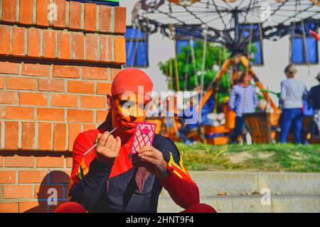 Street performer che mette sul suo make-up viso. Gli artisti di strada possono ingannare i passanti e intrattenere i turisti. Foto Stock