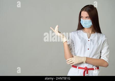 Una dottoressa in una maschera medica punta a un posto vuoto, copia spazio Foto Stock