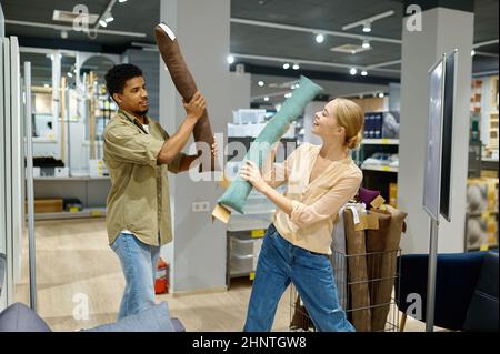 Coppia allegra che combatte con cuscino in negozio Foto Stock