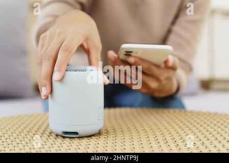 primo piano a portata di mano utilizzando il telefono che collega l'altoparlante bluetooth Foto Stock