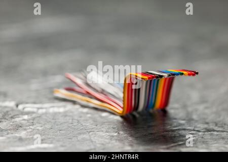 Primo piano di un cavo a nastro per computer corto, piegato e colorato su una superficie grigia ruvida con profondità di campo ridotta. Foto Stock