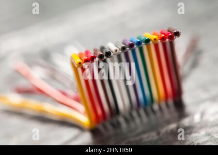 Primo piano estremo di un cavo a nastro per computer corto, piegato e colorato su una superficie grigia ruvida con profondità di campo ridotta. Foto Stock