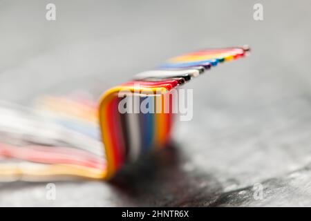 Primo piano di un cavo a nastro per computer corto, piegato e colorato su una superficie grigia ruvida con profondità di campo ridotta. Foto Stock