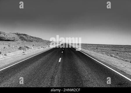 strada vuota attraverso il deserto della valle della morte sotto il cielo blu Foto Stock