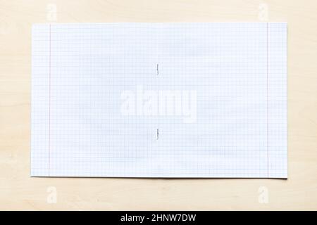vista dall'alto di un quaderno vuoto aperto con fogli quadrati con margini su asse di legno marrone chiaro Foto Stock
