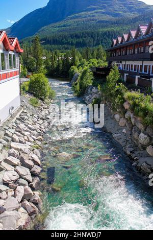 Fluendo le belle acque turchesi del fiume tra le case di Hemsedal, Viken, Buskerud, Norvegia. Foto Stock