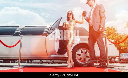 Autista aiutando vip donna o star fuori di limo sul tappeto rosso per un ricevimento Foto Stock