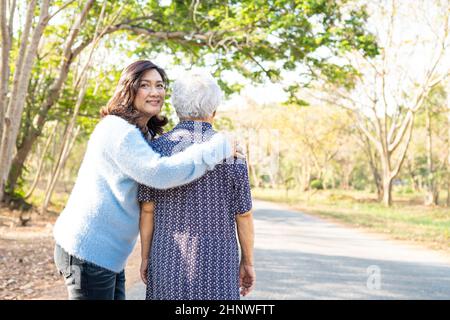 Aiuto e cura Asian anziano anziano o anziano donna anziana mentre cammina al parco in felice vacanza fresca. Foto Stock