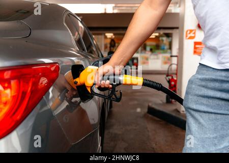 Giovane uomo, riempire il serbatoio diesel di auto dopo la fine riempire il gasolio e pagare il prezzo con le tasse in distributore di benzina per il trasporto del suo viaggio Foto Stock