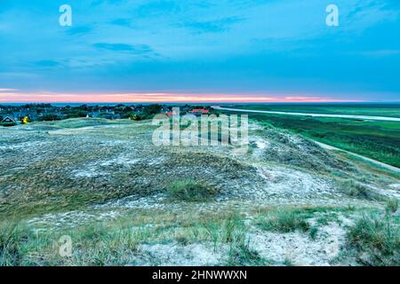 tramonto in fanoe con nuvole scure e villaggio sullo sfondo Foto Stock