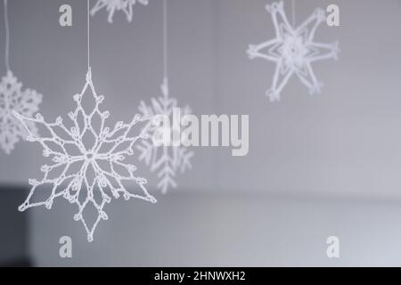 Decorazioni natalizie fatte a mano. Varietà di delicati fiocchi di neve in maglia bianca. Interni di Natale o Capodanno. Messa a fuoco selettiva. Foto Stock