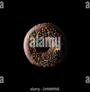 ciambelle al cioccolato con spolverette multicolore si levitano su sfondo nero Foto Stock