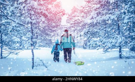 Padre e suo figlio camminano nella foresta innevata d'inverno. Concetto del rapporto di famiglia e vacanza. Foto Stock