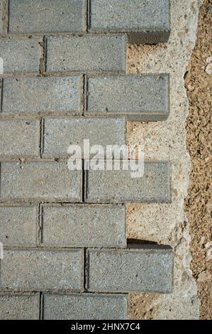 Pavimentazione in cemento acciottolato in costruzione. Posa di pezzi di pavimentazione interbloccanti Foto Stock