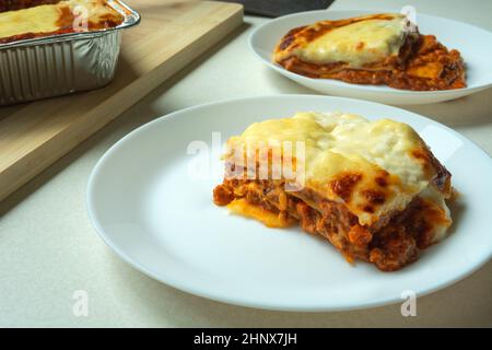 Pezzi di lasagna cotti su un piatto rotondo bianco Foto Stock