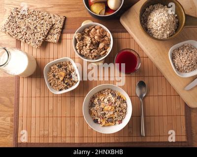 Ricca prima colazione con cereali biologici e ingredienti su un tavolo di legno, concetto di cibo sano Foto Stock