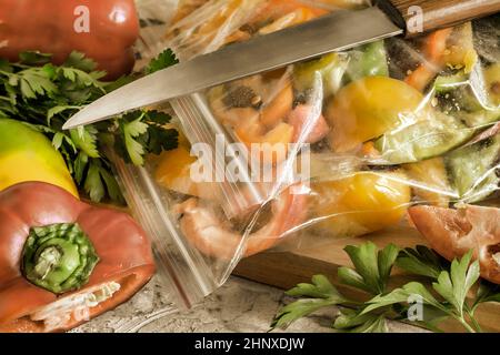 Affettato frutti maturi di peperone in sacchetti di cellophane, preparati per il congelamento e la conservazione a lungo termine nel comparto freezer del frigorifero. V. Anteriore Foto Stock