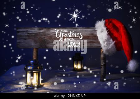 Segno con Calligraphy Inglese buon Natale e felice 2022. Tranquilla notte di Natale con neve e lampada. Foto Stock