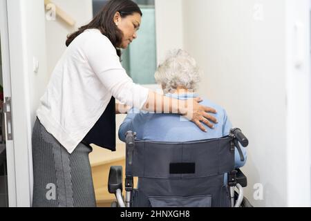 Aiuto dell'operatore sanitario asiatico o anziano anziana donna seduta sedia a rotelle sostenere le scale in casa. Foto Stock