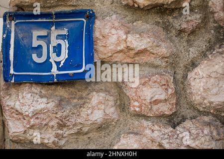 Targa numero 55 su una vecchia casa sporca muro. Foto Stock