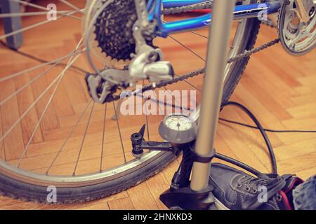 Il gonfiaggio del pneumatico di una bicicletta. Pompaggio di aria all'interno di una ruota di bicicletta. Home manutenzione della bicicletta. Servizio biciclette e mantenendo per la nuova stagione. Foto Stock