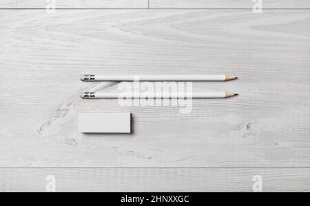 Due matite bianche e gomma su sfondo di legno. Disposizione piatta. Foto Stock