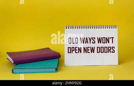 Carta bianca con l'iscrizione Old Ways non apre New Doors su un blocco note e uno sfondo giallo Foto Stock