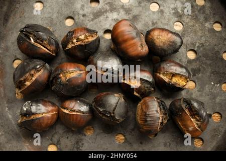 castagne arrosto nella tipica padella forata Foto Stock